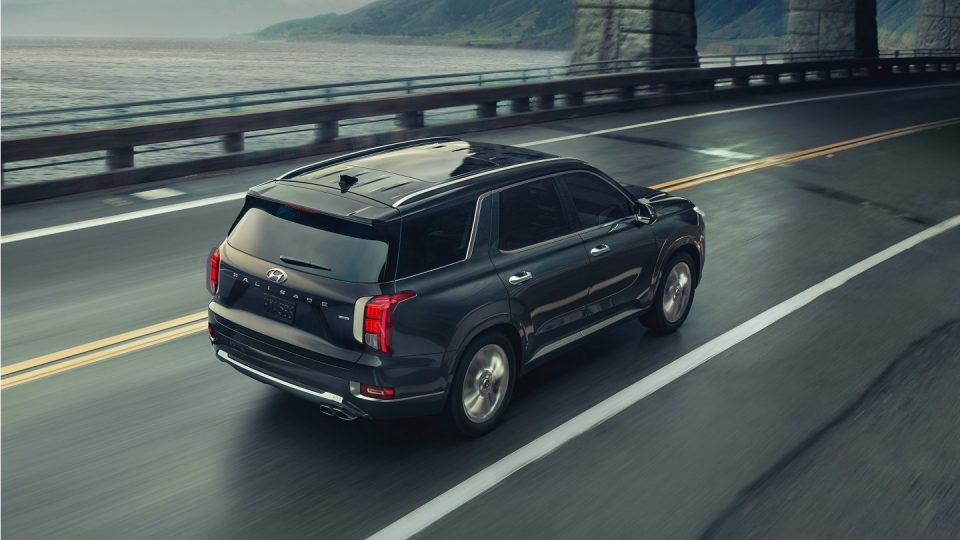 Black 2020 Hyundai Palisade driving along a bridge on a rainy day