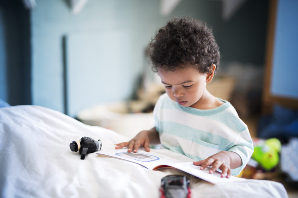 Cute little boy reading book at home