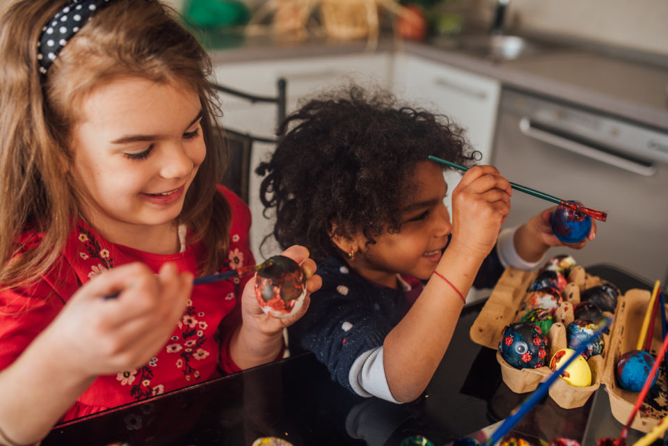 Happy young girls coloring Easter eggs at home