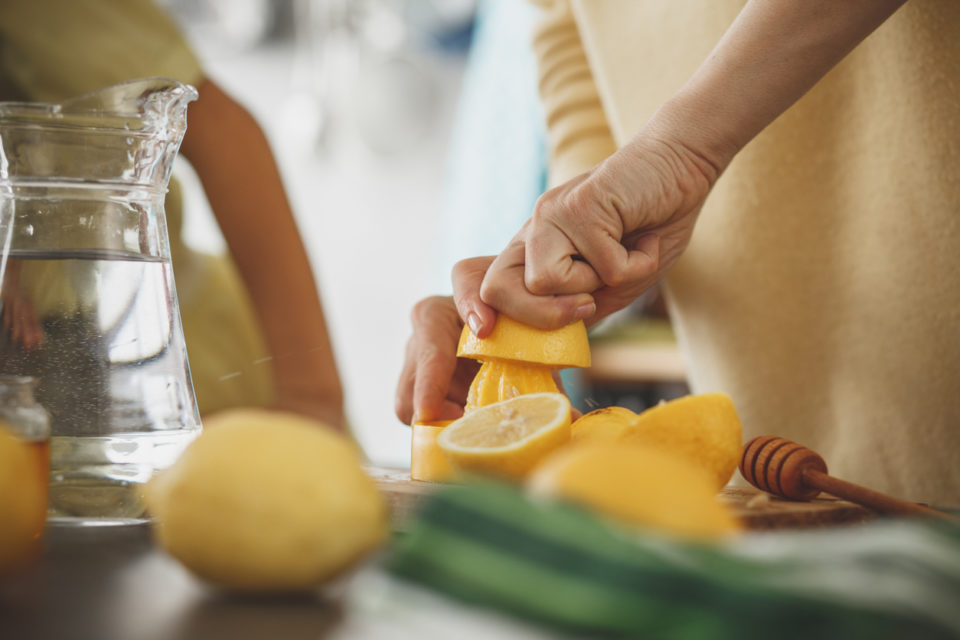 Close-up shot of a woman squeezing juice and making lemonade in the kitchen.