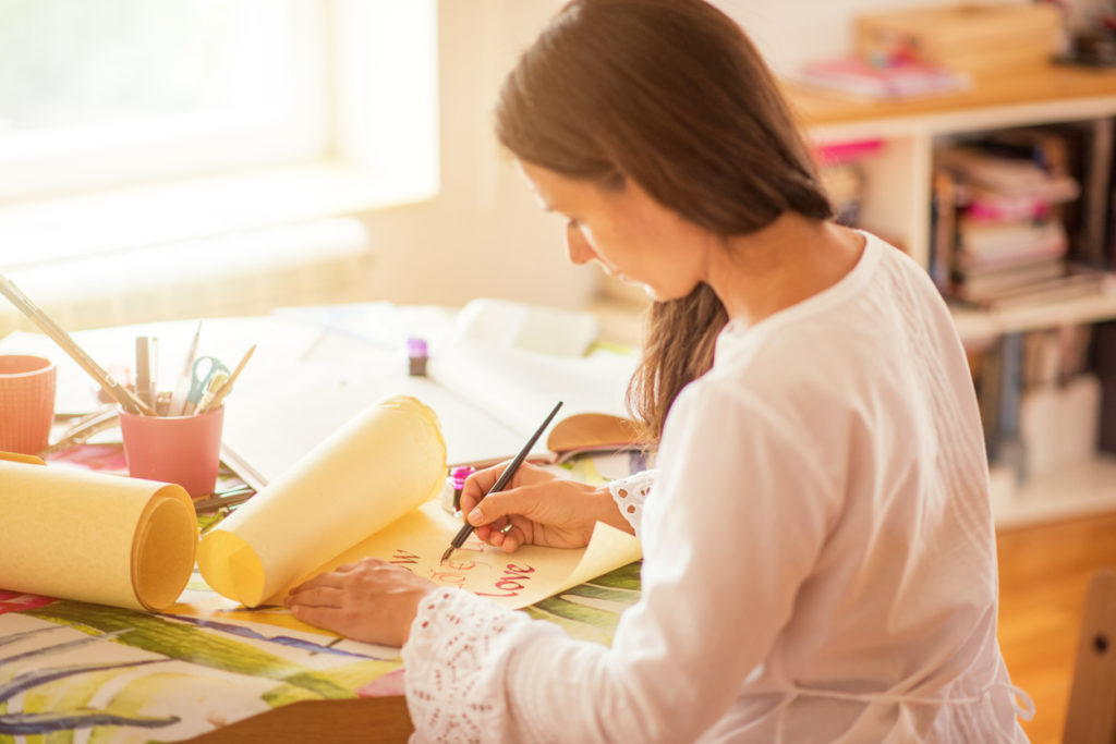 woman drawing with pen and ink in a sunny room