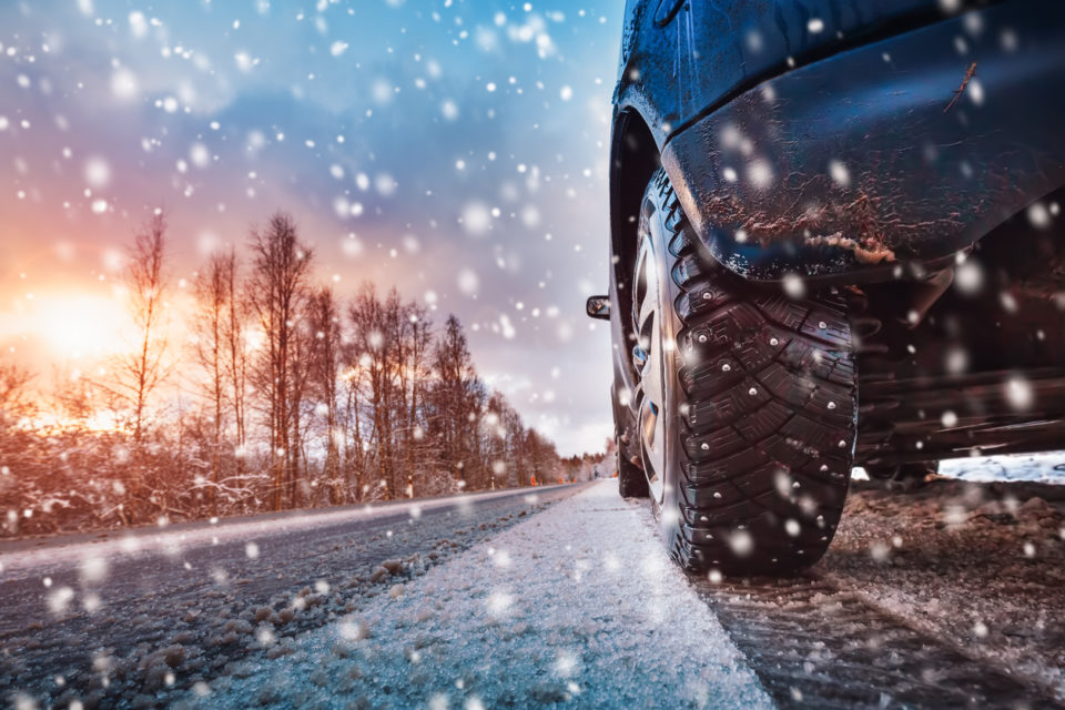 Car tires on winter road covered with snow. Vehicle on snowy way in the morning at snowfall