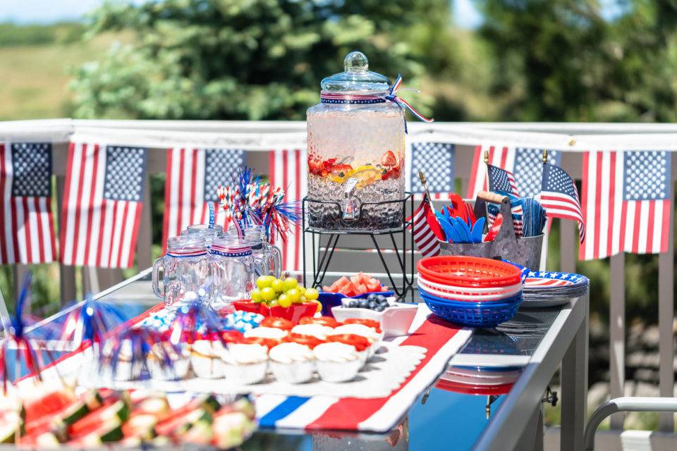 Table with food and drinks set for celebrating July 4th on the back patio.