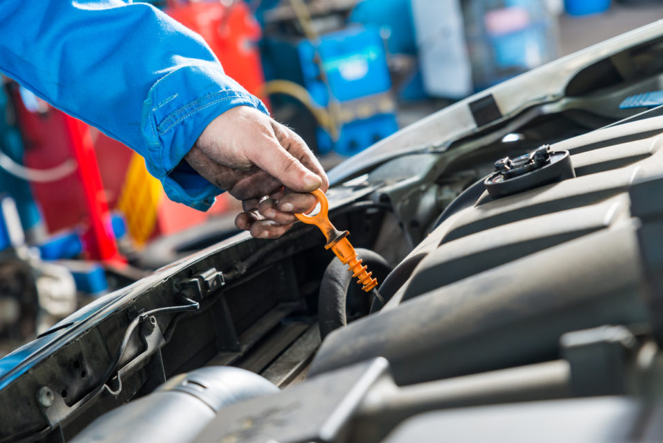 Human hand is checking oil status with dipstick