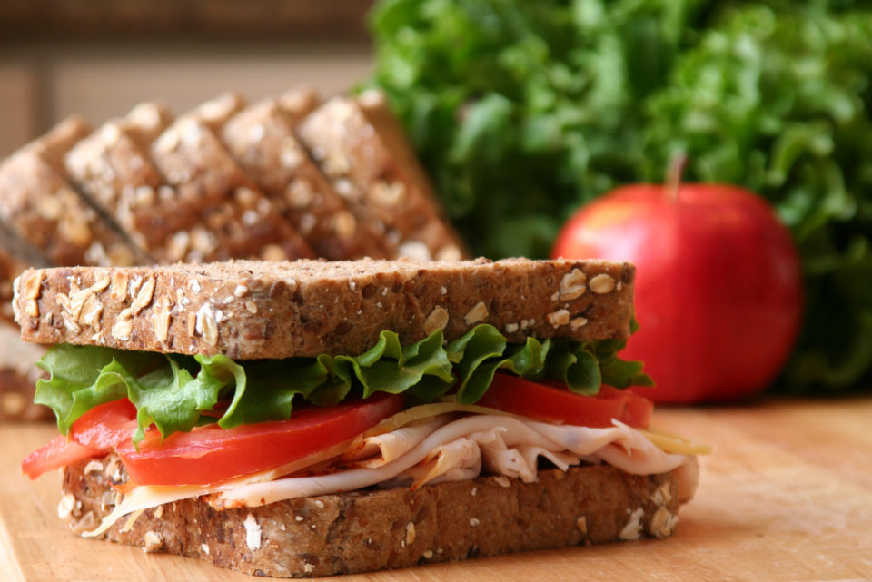 Healthy sandwich made with whole grain bread, lettuce, tomato, cheese, and roasted chicken slices.
