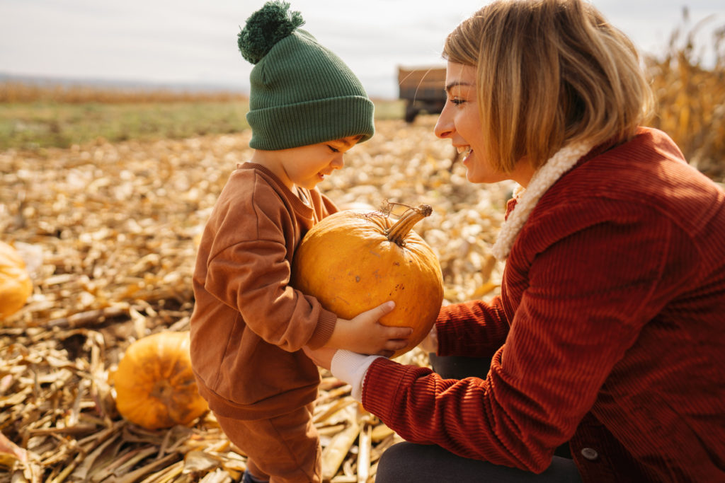 young mother and her son collecting pumpkins