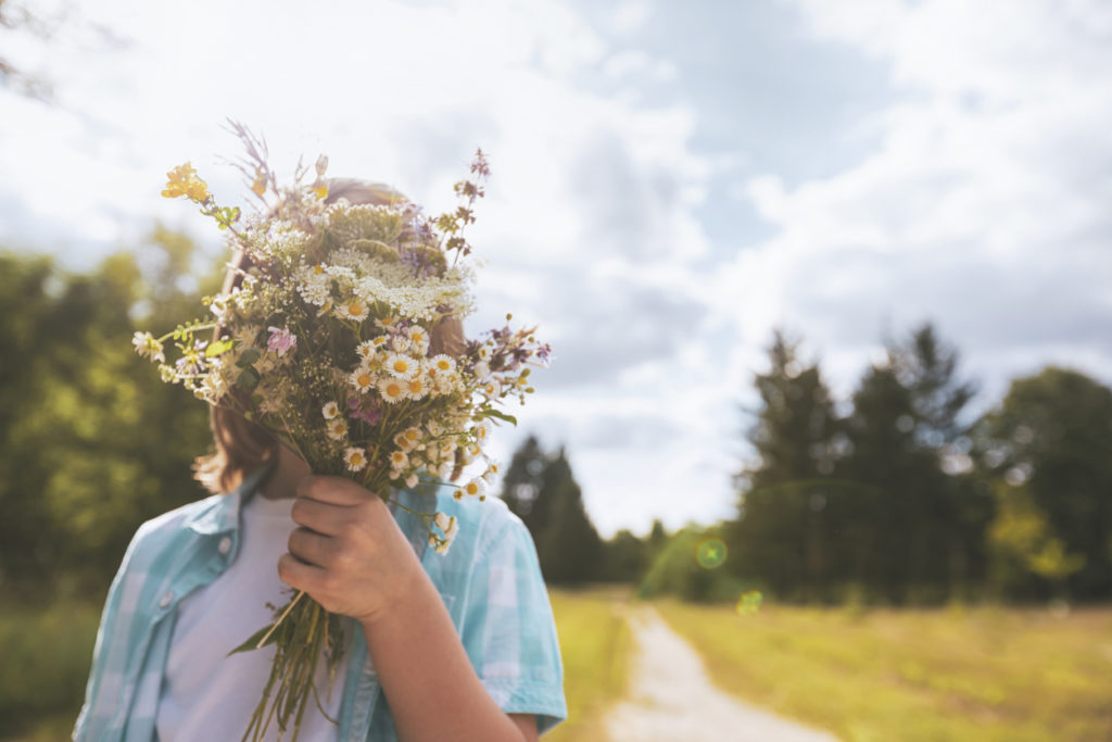 Child hidden behind a bouquet of wildflowers