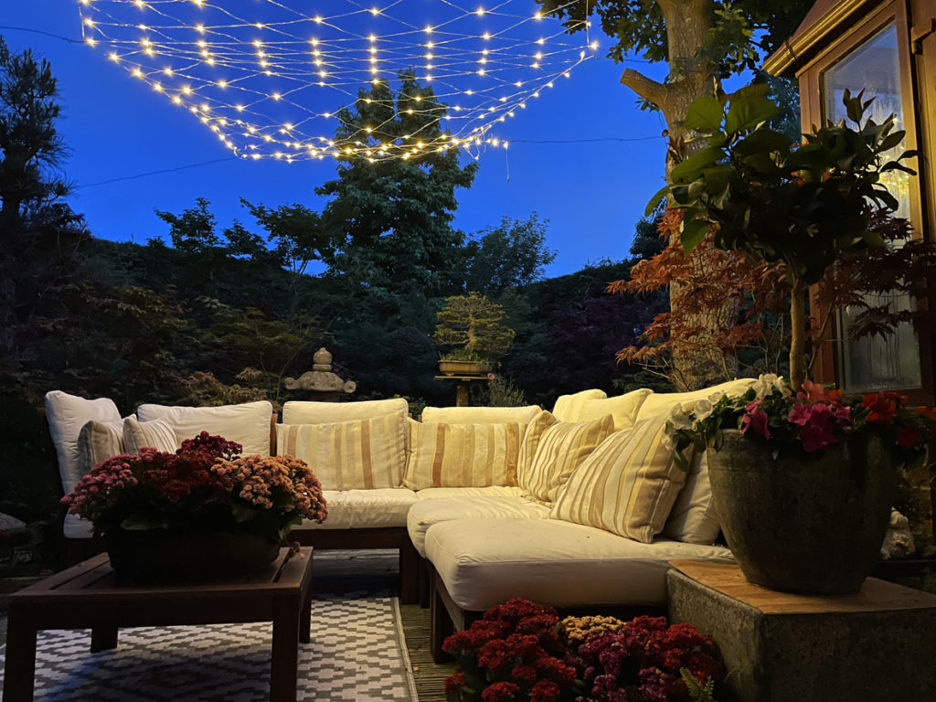 backyard patio with seating and string lights at night