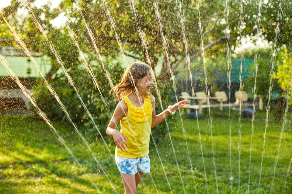 happy kids playing in sprinkler