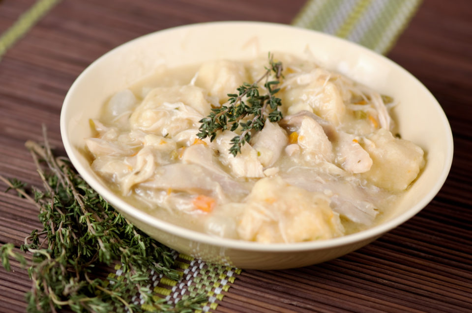 Chicken and dumplings garnished with a sprig of thyme