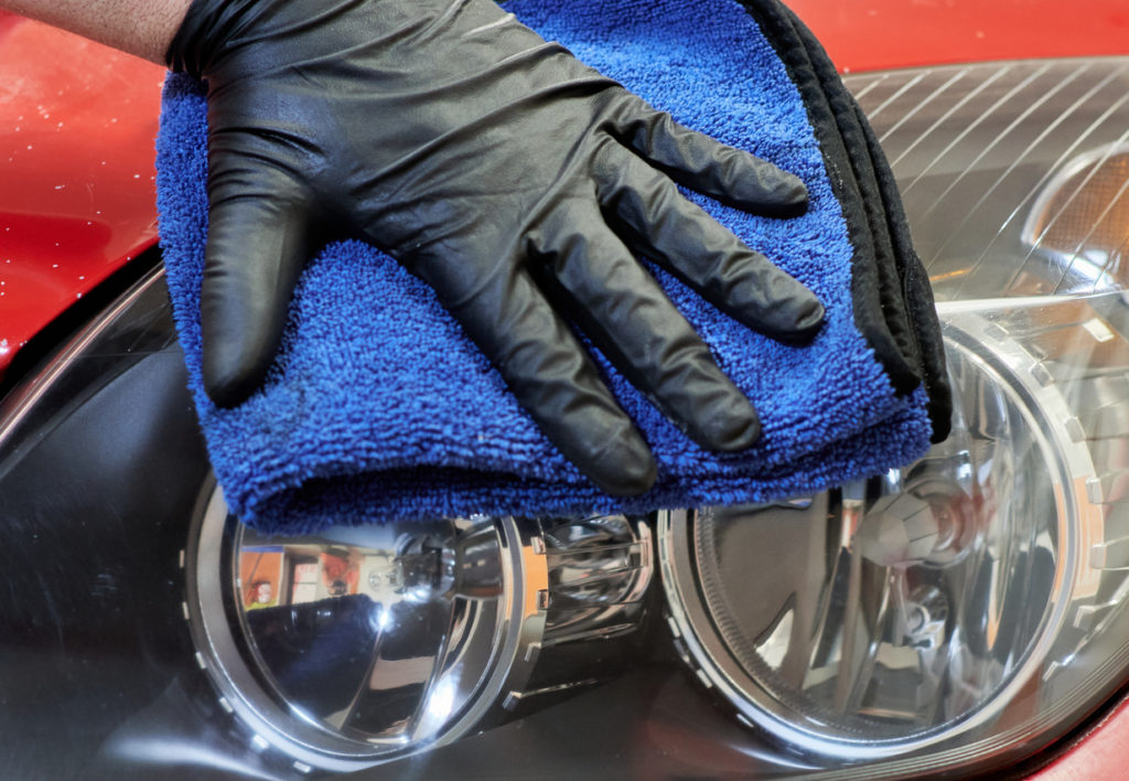gloved hand cleaning a car's headlight