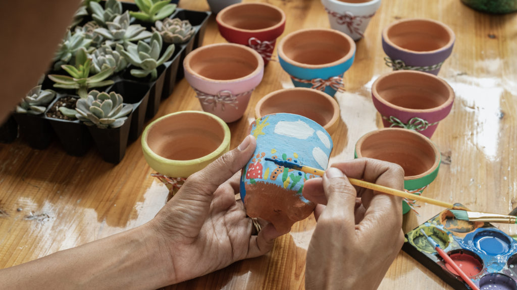 Hands of a Latin mulatto woman, painting clay pots to plant succulent plants